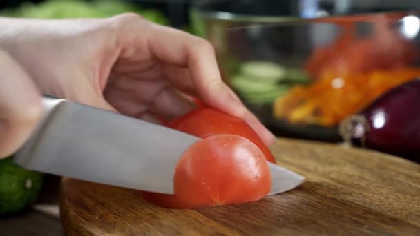 Ženy ruce pomocí kuchyňského nože krájení čerstvých rajčat na dřevěné řezací desce. Zdravé jídlo. Krájené rajče. — Stock video