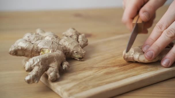 Men hands cut with a knife ginger root on wooden cutting board — Stock Video