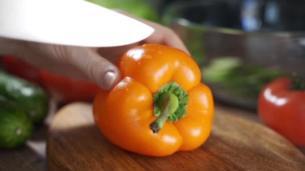 Video närbild skära apelsin bell pepper i små bitar. Beredning av peppar för matlagning. — Stockvideo
