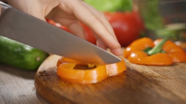 Video närbild skära apelsin bell pepper i små bitar. Beredning av peppar för matlagning. — Stockvideo