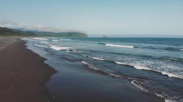 Летним днем беспилотник летит над лазурным морем с волнами и песчаным побережьем — стоковое видео