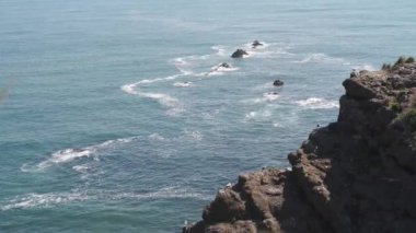 Dalgaların yukarıdan görünüşü mavi bir okyanusta kayalara çarpıyor. Deniz dalgaları güzel sahil manzaralı İHA 4K görüntüsü..