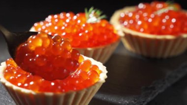 Kavanozda kırmızı havyar, masada. Siyah arkaplanda