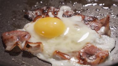 Kızarmış pastırma dilimlerine tuz dökmek ve tavada iki yumurta, tavada çıtır çıtır pastırma şeritleri..