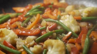 Sebzeleri tavada pişiren şefi kapat. Kızartma tavasında pişirilen karışık sebzeler..