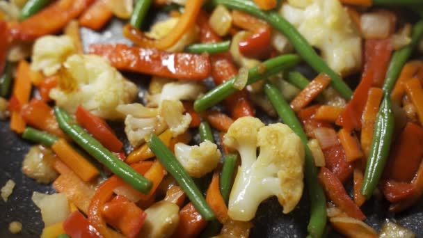 Smażyć mrożone warzywa na patelni. Ziemniaki, cukinia, marchew, cebula, fasola, groszek. — Wideo stockowe