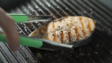 Izgarada kurutulmuş salman bifteğini çevirip mangal dumanını koklamak.