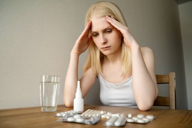 Genç bir kadın koronavirüs hastası. Masada çeşitli ilaçlarla oturuyor.