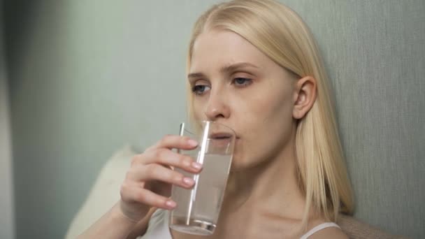 Κοντινό πλάνο μιας νεαρής γυναίκας να παίρνει χάπια με ένα ποτήρι νερό. Υγειονομική και ιατρική έννοια. — Αρχείο Βίντεο
