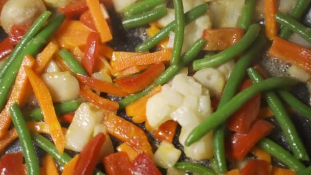 Zelená a barevná čerstvá zelenina v železné pánvi, dušená zelenina. Domácí vegetariánské jídlo s zeleninou, asijská kuchyně. Připravujeme večeři s mrkví, brokolicí.