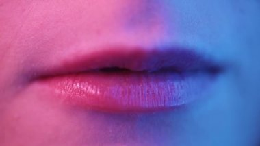 Güzel seksi model dudaklar, yakın plan, disko. Kadın ağzı kapalı. Metalik ruj makyajı. Mor ve mavi ultraviyole ışıklar. Yavaş çekim UHD videosu