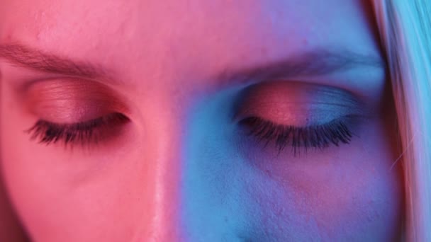 Extreme Nahaufnahme der Iris des menschlichen Auges unter Neonlicht 4K. Weiblich mit wunderschönem Make-up, Glitzerschatten. Die Augen der Frauen ziehen sich zusammen. Nachtleben, Nachtklubkonzept — Stockvideo