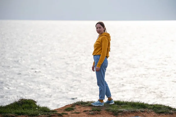 Sakin bir denizin kıyısında genç bir kadın duruyor. Deniz manzarasının tadını çıkar. Deniz kenarında dinlen..