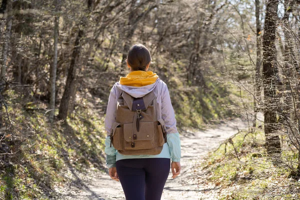 Uma mulher com uma mochila grande caminha ao longo de um caminho florestal. Anseio por aventura e lugares inexplorados. — Fotografia de Stock