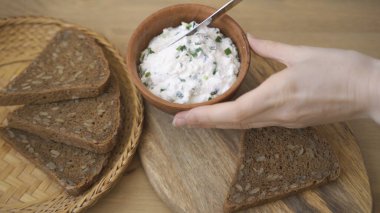 Ekmeğin üzerine soğanlı krem peynir sürüyorum..