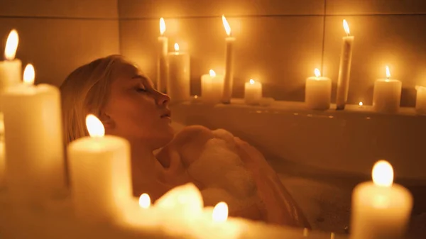 Primer plano de una joven tomando un baño rodeado de velas. Fotos de stock