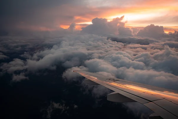 Ala di aeroplano su nuvole spesse e tramonto. Vista dal finestrino dell'aereo. Viaggi e ricreazione all'estero — Foto Stock