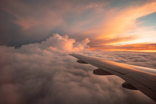 La vista dal finestrino dell'aereo alle nuvole e al tramonto. Ala di aeroplano sopra spesse nuvole rosa e arancioni. Splendida vista mozzafiato — Foto Stock