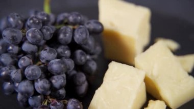 Gurme parmesan peyniri siyah bir taş tabakta ceviz ve üzümle servis edilir.