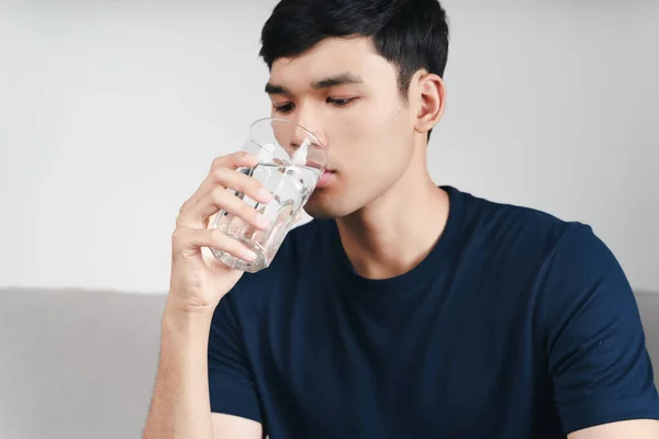 Schöner Asiatischer Mann Trinkt Ein Glas Wasser Auf Dem Sofa — Stockfoto