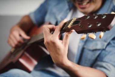 Yakışıklı Asyalı adamın oturma odasında gitar çalışmasının ya da gitar çalmasının keyfini çıkarın. 