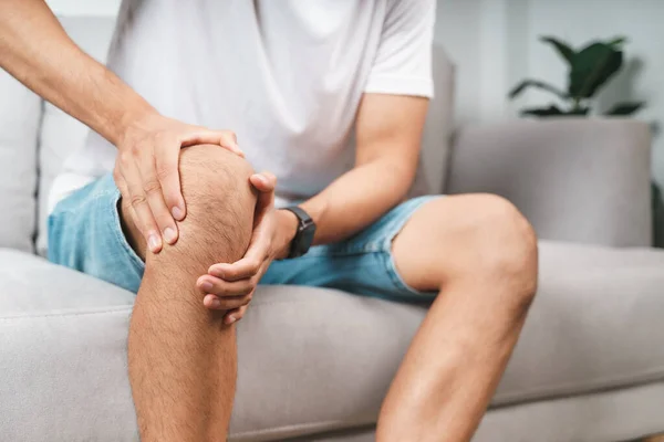 Mannen Som Lider Knäsmärta Sitter Soffan Och Masserar Sitt Smärtsamma — Stockfoto