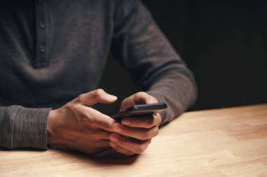 Ahşap masada akıllı telefon kullanan bir adamın fotoğrafı, arama, tarama, sosyal medya, mesaj, e-posta, internet dijital pazarlama, online alışveriş