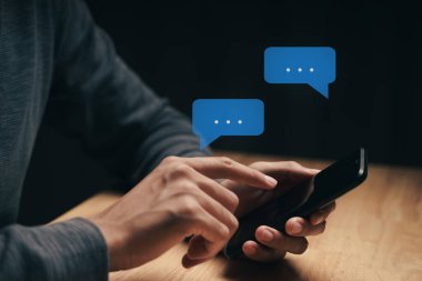 Genç adam akıllı telefon daktilosu kullanıyor, sohbet kutusu simgeleriyle sohbet ediyor. Sosyal Ağ, teknoloji kavramı