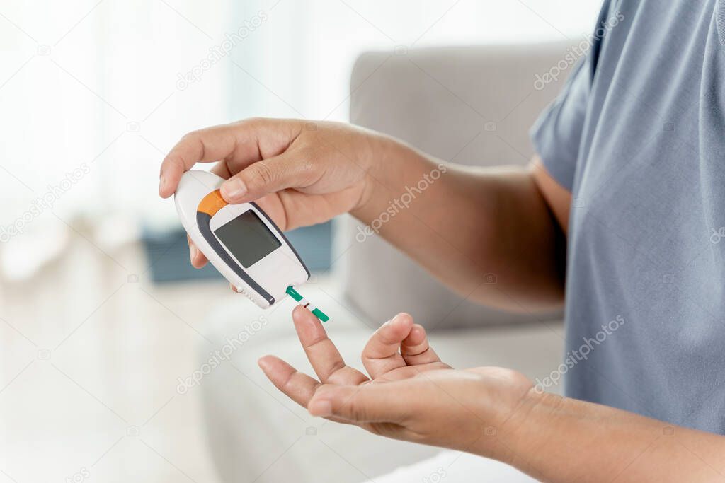 Mature Asian woman checking blood sugar level by Digital Glucose meter, Healthcare and Medical, diabetes, glycemia concept