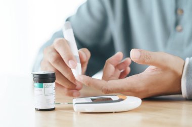 Asyalı adam kan şekeri seviyesini Glikoz metre, Sağlık ve Sağlık, Diyabet, glisemi konseptine göre ölçmek için parmak üzerine mızrak kullanıyor.