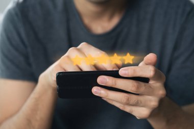 Müşterinin akıllı telefondan 5 yıldızlı reyting vermesine yakın çekim. İnceleme, Hizmet derecesi, memnuniyet, Müşteri hizmetleri deneyimi ve memnuniyet anketi konsepti