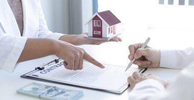 Emlakçı ya da satış müdürü, ev satın alma anlaşmalarını sigorta ile imzalayan müşterilere satın alma sözleşmesini imzalama şartlarını ve şartlarını önerdi..