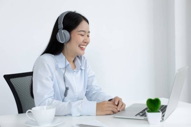 Asyalı kadın internet üzerinden neşeli bir gülümsemeyle çalışıyor, evde kalıyor, Yeni Normal, Covid-19 Coronavirus, Sosyal Mesafe, İnternet Öğrenimi.