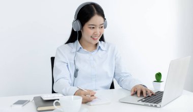 Asyalı kadın internet üzerinden neşeli bir gülümsemeyle çalışıyor, evde kalıyor, Yeni Normal, Covid-19 Coronavirus, Sosyal Mesafe, İnternet Öğrenimi.