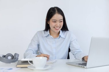 Asyalı kadın internet üzerinden neşeli bir gülümsemeyle çalışıyor, evde kalıyor, Yeni Normal, Covid-19 Coronavirus, Sosyal Mesafe, İnternet Öğrenimi.