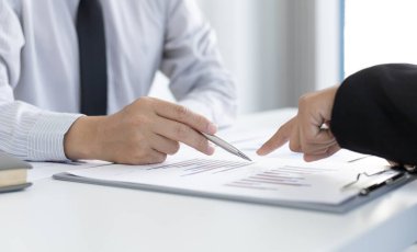 Şirketin gelir grafiğiyle ilgili iş adamları, yöneticiler ve muhasebecilerden oluşan bir ekiple ofiste dizüstü bilgisayarlar, hesap makineleri ve finans konseptiyle bir araya gelmek.