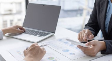 Şirketin gelir grafiğiyle ilgili iş adamları, yöneticiler ve muhasebecilerden oluşan bir ekiple ofiste dizüstü bilgisayarlar, hesap makineleri ve finans konseptiyle bir araya gelmek.