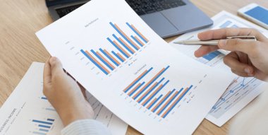 Muhasebe işadamları gelir-gider hesapları yapıyor ve gayrimenkul yatırım verilerini analiz ediyor. Bir masada çalışıyor. Bilgisayarlı, mali ve vergi sistemli grafikleri ve hesap makineleri var..