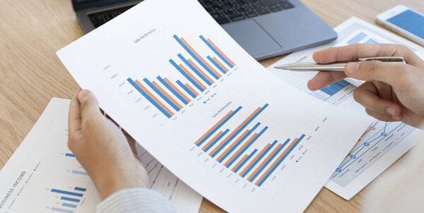 Бухгалтерские бизнесмены рассчитывают доходы-расходы и анализируют данные инвестиций в недвижимость, он работает на столе есть графики и калькуляторы с ноутбуком, финансовыми и налоговыми системами концепции.