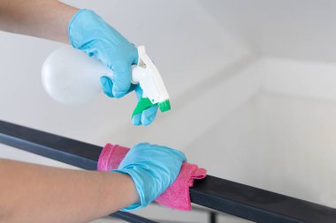 Genç Asyalı erkek çalışanlar parmaklıkları veya verandayı temizlemek, virüs salgınları sırasında patojen önleme veya temizlik yapmak, bir restoranı veya kahve dükkanını temizlemek için alkole bulanmış bir havlu kullanıyorlar..