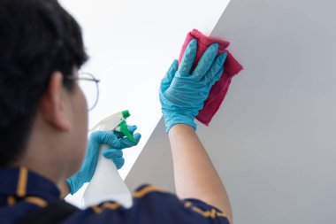 Çalışanların elleri beyaz duvarları siliyordu. Duvarı temizlemek için nemlendirilmiş bir havlu kullanıyordu. Mesajlaşma alanı, beyaz arka plan virüs salgını sırasında mikropları yok ediyordu..