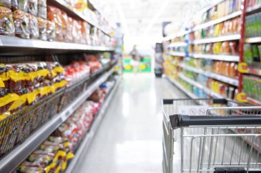 Süpermarketteki alışveriş arabası, alışveriş merkezlerindeki bulanık fotoğraf, pazardaki araba, düzenli bir ekran için raflara çeşitli ürünler yerleştiriliyor..