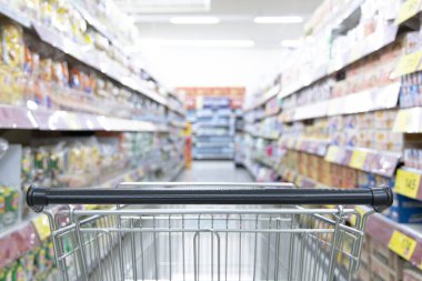 Süpermarketteki alışveriş arabası, alışveriş merkezlerindeki bulanık fotoğraf, pazardaki araba, düzenli bir ekran için raflara çeşitli ürünler yerleştiriliyor..