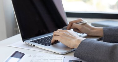 Bilgisayarın klavyesine, teknoloji ve internet iletişimine basan bir kadının yakın plan fotoğrafı. Finans uzmanları emlak gelirlerini hesaplamak ve kontrol etmek için dizüstü bilgisayar kullanıyor..