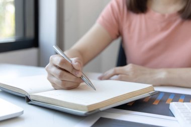 Virüs yayılırken öğrenme sürecinde, Asyalı genç kadının çevrimiçi eğitimi örnek grafiklerle verileri analiz ediyor ve cevaplarını not defterlerine, çevrimiçi öğrenim ve eğitime, ev ödevlerine yazıyorlar..