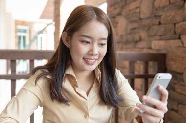 Asyalı kadın çalışanlar akıllı telefonlar aracılığıyla pazar verilerini analiz ediyorlar ve şirketin finansmanını hesaplamak için dizüstü bilgisayarları evde, evde ve yeni normal kavramlarla çalışan özel bir ofiste bulunuyorlar..