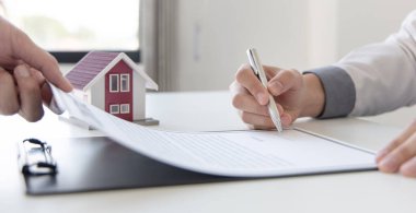 Emlakçı ya da satış müdürü, ev satın alma anlaşmalarını sigorta ile imzalayan müşterilere satın alma sözleşmesini imzalama şartlarını ve şartlarını önerdi..