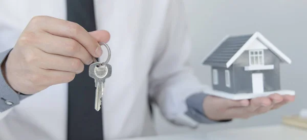 Sales manager or real estate agent prepares to hand over the keys and the house together with the insurance to the customer, Attention to property services and insurance concept.