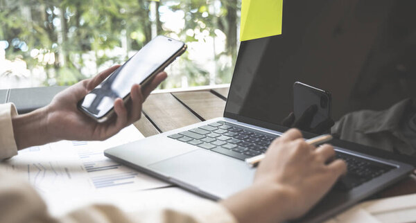 Financial businesswomen use laptop and smart phone to analyze marketing strategies and real estate data to reduce company taxes for their customers, Accounting and Tax concept.