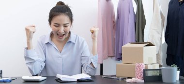 Genç Asyalı kadın tebriklerini sundu ve gülümsedi. İnternetten kıyafetlerini sipariş etti, iyi hissetti, sosyal medyada kıyafet satma ya da internet üzerinden satış işi yaptı..